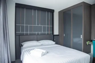 a bedroom with a large white bed with a black headboard at Hallton Hotel Bangkok in Bangkok