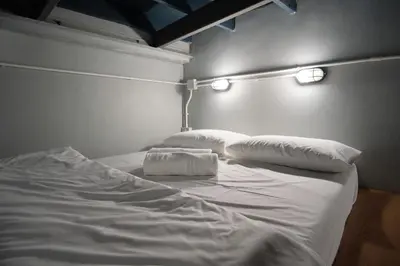 a white bed with two pillows and lights on it at Private Stay Hostel in Bangkok