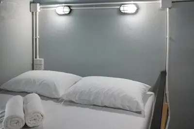 a bed with two pillows and two lights on it at Private Stay Hostel in Bangkok