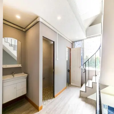 a bathroom with a sink and a staircase in a house at Bossa House Hostel & Cafe in Bangkok