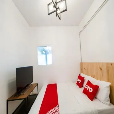 a bedroom with a bed with red pillows and a tv at Bossa House Hostel & Cafe in Bangkok
