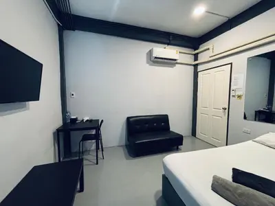 a room with a bed and a black chair at Udomsuk Inn & Cafe - BTS Udomsuk in Bangkok