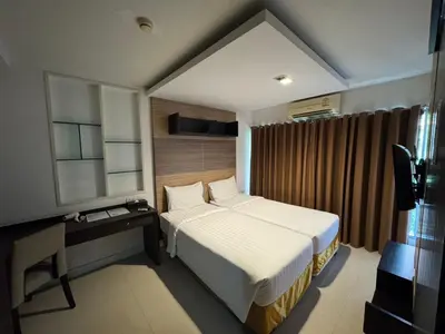 a bedroom with a white bed and a desk and a window at Palette Bella B All Suites Bangkok Hotel in Bangkok