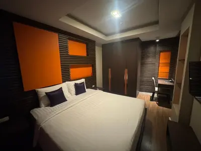 a bedroom with a large white bed and a desk at Palette Bella B All Suites Bangkok Hotel in Bangkok