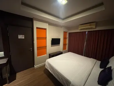 a bedroom with a bed and a door and a television at Palette Bella B All Suites Bangkok Hotel in Bangkok
