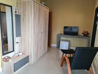 a living room with a chair and a cabinet and a television at The Lantern Suites in Ban Song Hong