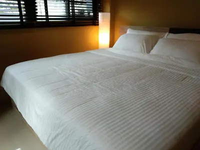 a large white bed in a bedroom with a window at The Lantern Suites in Ban Song Hong