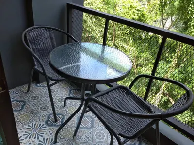 a glass table and two chairs on a balcony at The Lantern Suites in Ban Song Hong