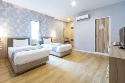 a hotel room with two beds and a television at Leela Orchid Hotel in Bangkok