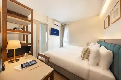 a hotel room with a bed and a table and a bed at SOVA Hotel Bangkok in Bangkok