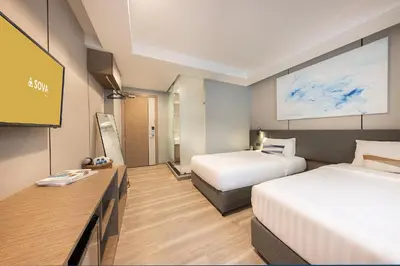 a hotel room with two beds and a tv at SOVA Hotel Bangkok in Bangkok