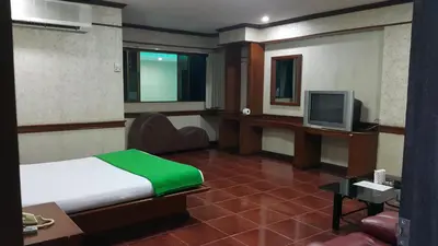 a hotel room with a bed and a television at West Wing Mansion in Bangkok