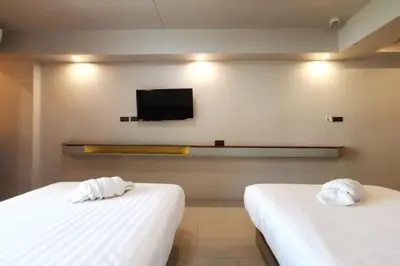 two beds in a room with a tv on the wall at A Sleep Bangkok Sathorn in Bangkok