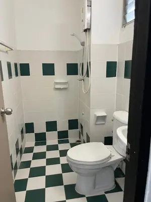 a bathroom with a toilet and a green and white checkered floor at N11Hotel in Bangkok