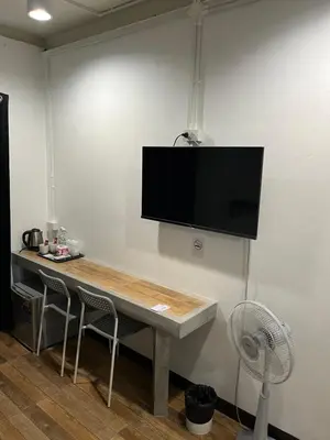 a room with a table with a tv on a wall at N11Hotel in Bangkok
