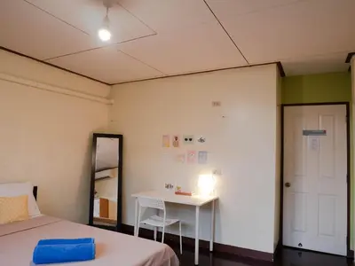 a bedroom with a bed and a table and a mirror at Chan Cha La 99 Hostel in Bangkok