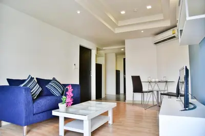 a living room with a blue couch and a table at The Kaze 34 Hotel and Serviced Residence in Bangkok