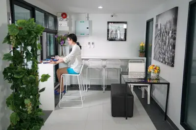 a woman sitting at a bar in a room at Ma Non Nont Hotel & Apartment in Nonthaburi