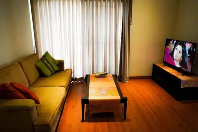 a living room with a couch and a table and a tv at Siam Bright Suite in Bangkok