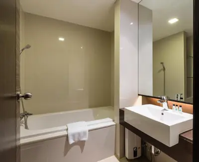 a bathroom with a white tub and a sink at Jasmine Grande Residence in Bangkok
