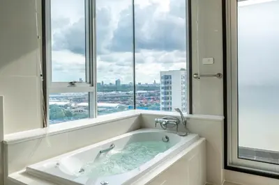 a bathroom with a bath tub with a large window at Jasmine Grande Residence in Bangkok
