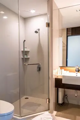 a bathroom with a shower and a toilet and a sink at Jasmine Grande Residence in Bangkok