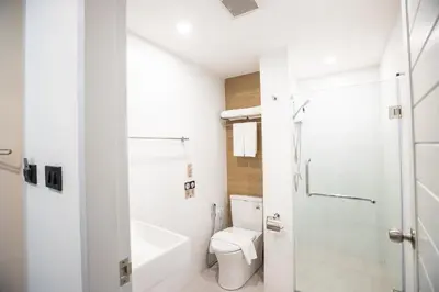 a white bathroom with a toilet and a shower at Cubic Bangna in Bangkok