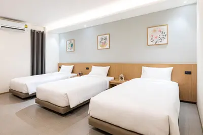 two beds in a hotel room with white sheets at Cubic Bangna in Bangkok