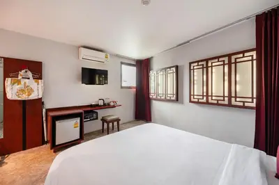 a bedroom with a large white bed and a table at Ruamchitt Plaza Hotel in Bangkok
