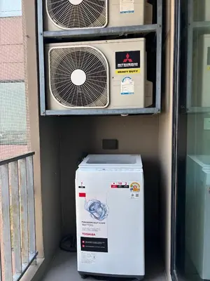 a refrigerator in a room with two air conditioners at The Gallery condominium in Samut Prakan