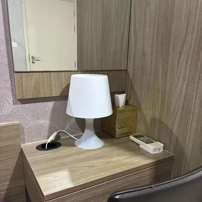 a lamp on a table with a mirror and a phone at The Gallery condominium in Samut Prakan