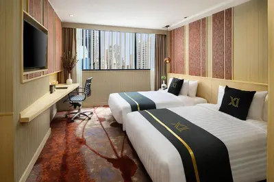 a hotel room with two beds and a television at Eleven Hotel Bangkok Sukhumvit 11 in Bangkok