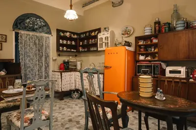 a kitchen with a table and an orange refrigerator at Lhong Yaowarat hostel in Bangkok