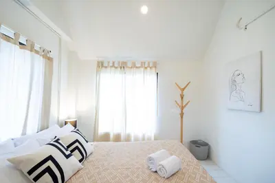 a white bedroom with a bed with black and white pillows at Bai Bua House Chatuchak in Ban Zong Katiam