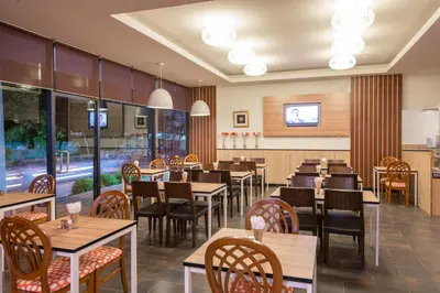 a restaurant with wooden tables and chairs and windows at Marsi Hotel Bangkok in Bangkok