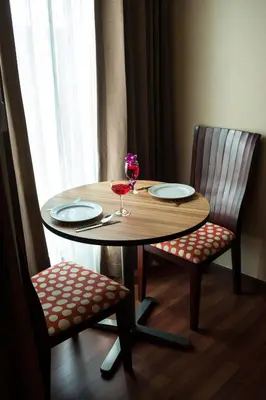 a wooden table with two chairs and a glass of wine at Marsi Hotel Bangkok in Bangkok