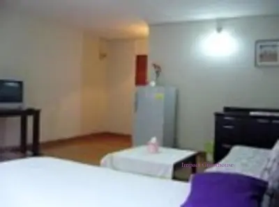 a room with two beds and a refrigerator at Poppular Palace Don Mueang Bangkok in Bangkok