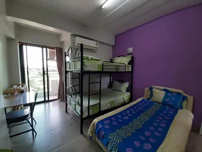 a bedroom with purple walls and a bed and a desk at Vanlisut Hotel Ngamwongwan in Nonthaburi
