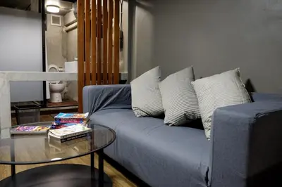 a living room with a blue couch and a glass table at In a Box Hostel in Bangkok