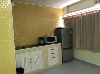 a small kitchen with a microwave and a refrigerator at Baan Khun Rak in Bangkok
