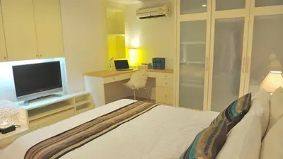 a bedroom with a bed and a desk with a television at Duplex 21 Apartment in Bangkok