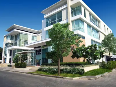 a large white building with a tree in front of it at Duplex 21 Apartment in Bangkok