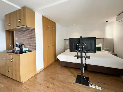 a bedroom with a bed and a kitchen with a sink at Pentafield City Residence in Amphoe Phra Khanong