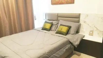 a bedroom with a large bed with two green pillows at The Excel Groove Condo at Lasalle 52 in Bangkok