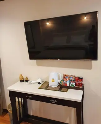 a tv hanging on a wall with a table at Cana Boutique Hotel in Bangkok