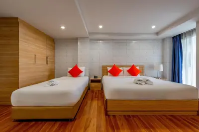two beds in a room with wood floors and red pillows at 7 Days Premium Hotel at Icon Siam Station - No Parking in Bangkok