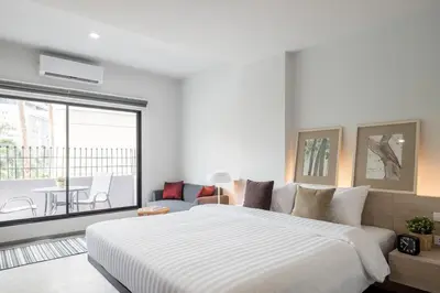 a bedroom with a large white bed and a balcony at China Cozy Asoke in Bangkok