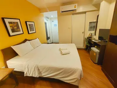 a bedroom with a large white bed with a desk at Vinary Hotel Sukhumvit in Bangkok