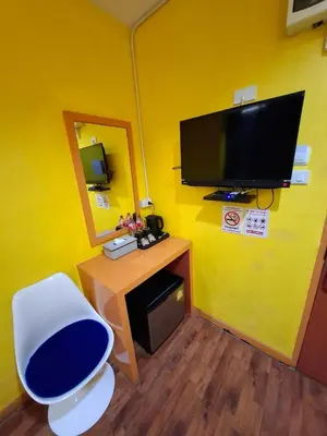 a room with a yellow wall with a tv and a chair at Wow Guesthouse in Bangkok