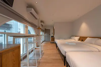 a hotel room with three beds and a window at Boxpackers Pratunam in Bangkok